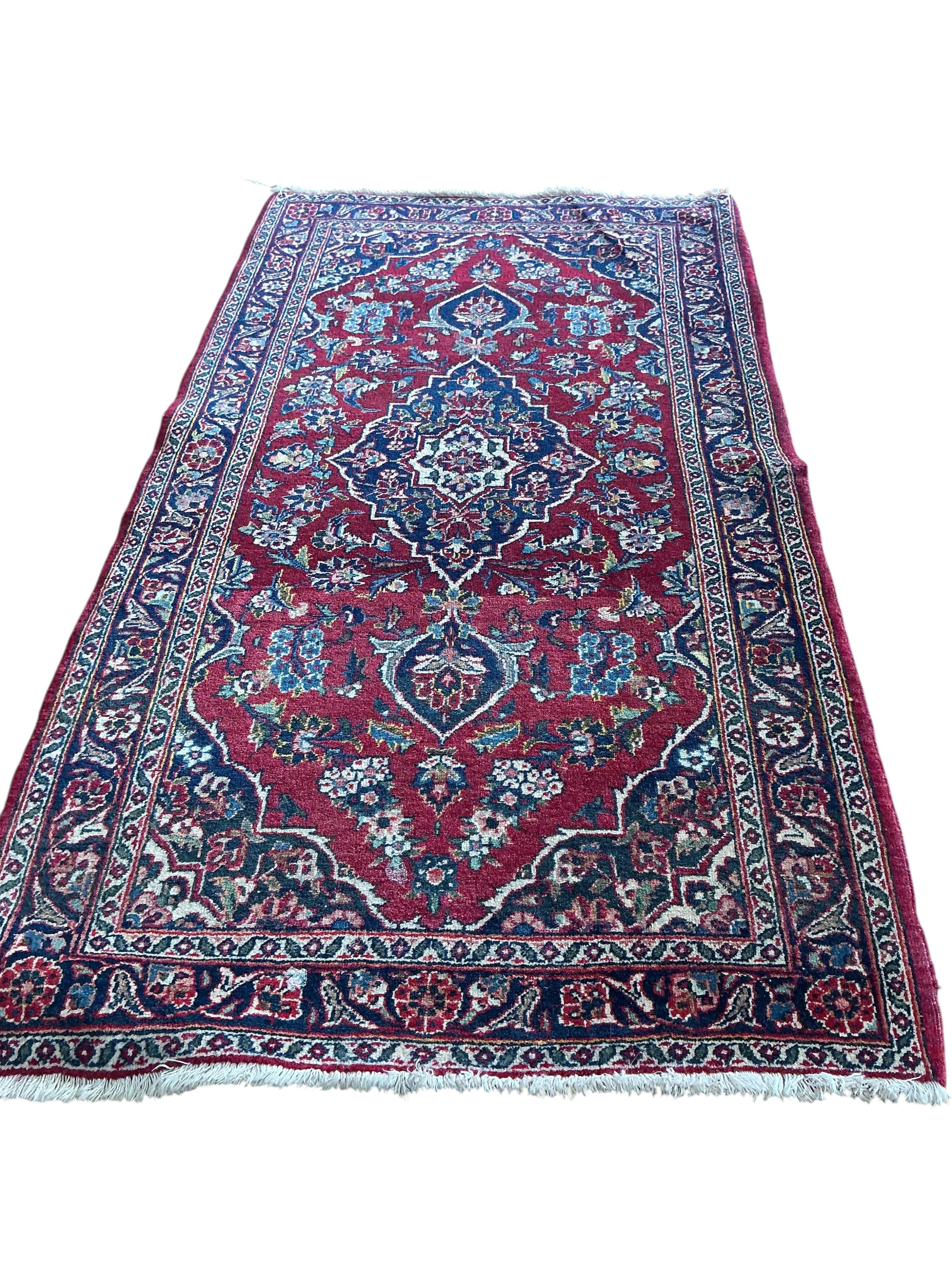 A North West Persian burgundy ground rug, 130 x 70cm